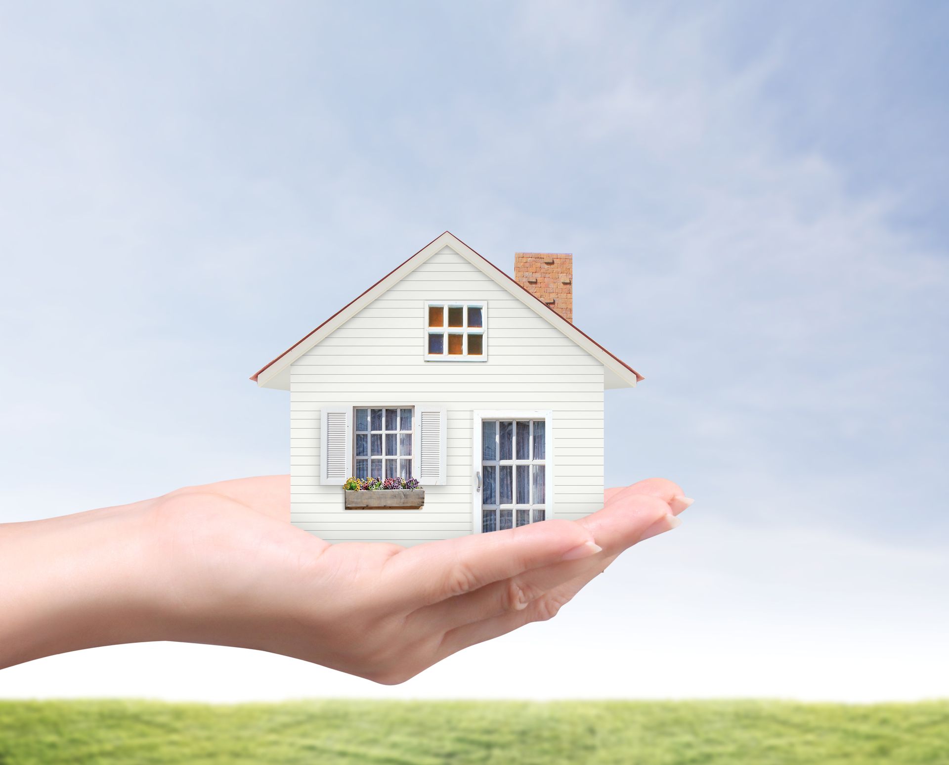 A person is holding a small white house in their hand.