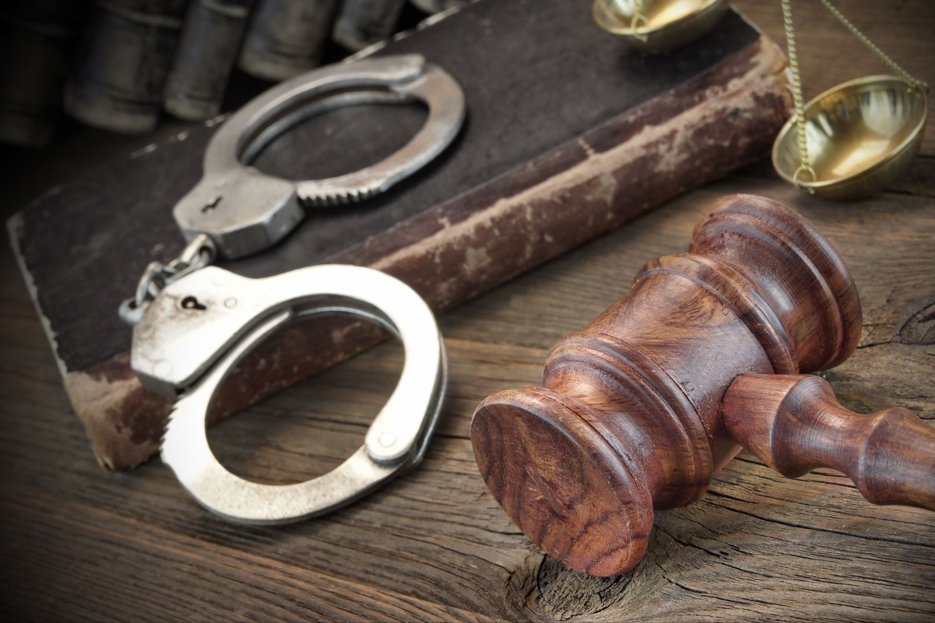 A pair of handcuffs sitting on top of a book next to a judge 's gavel.