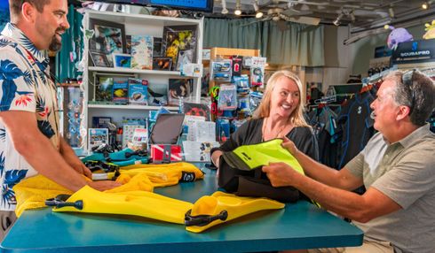 A group of people are sitting at a table in the dive shop.