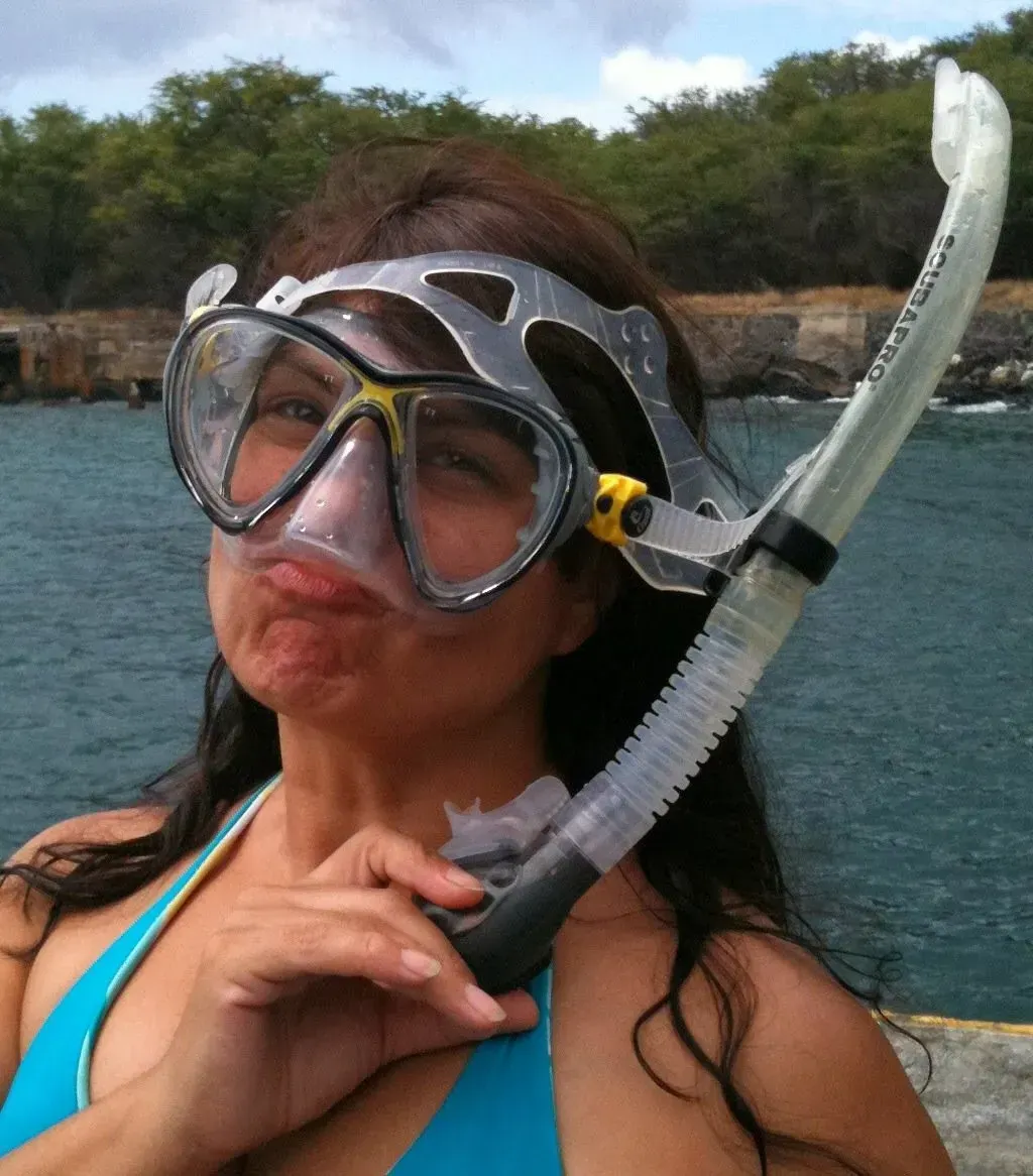 A woman in a blue bikini is wearing a mask and holding a snorkel