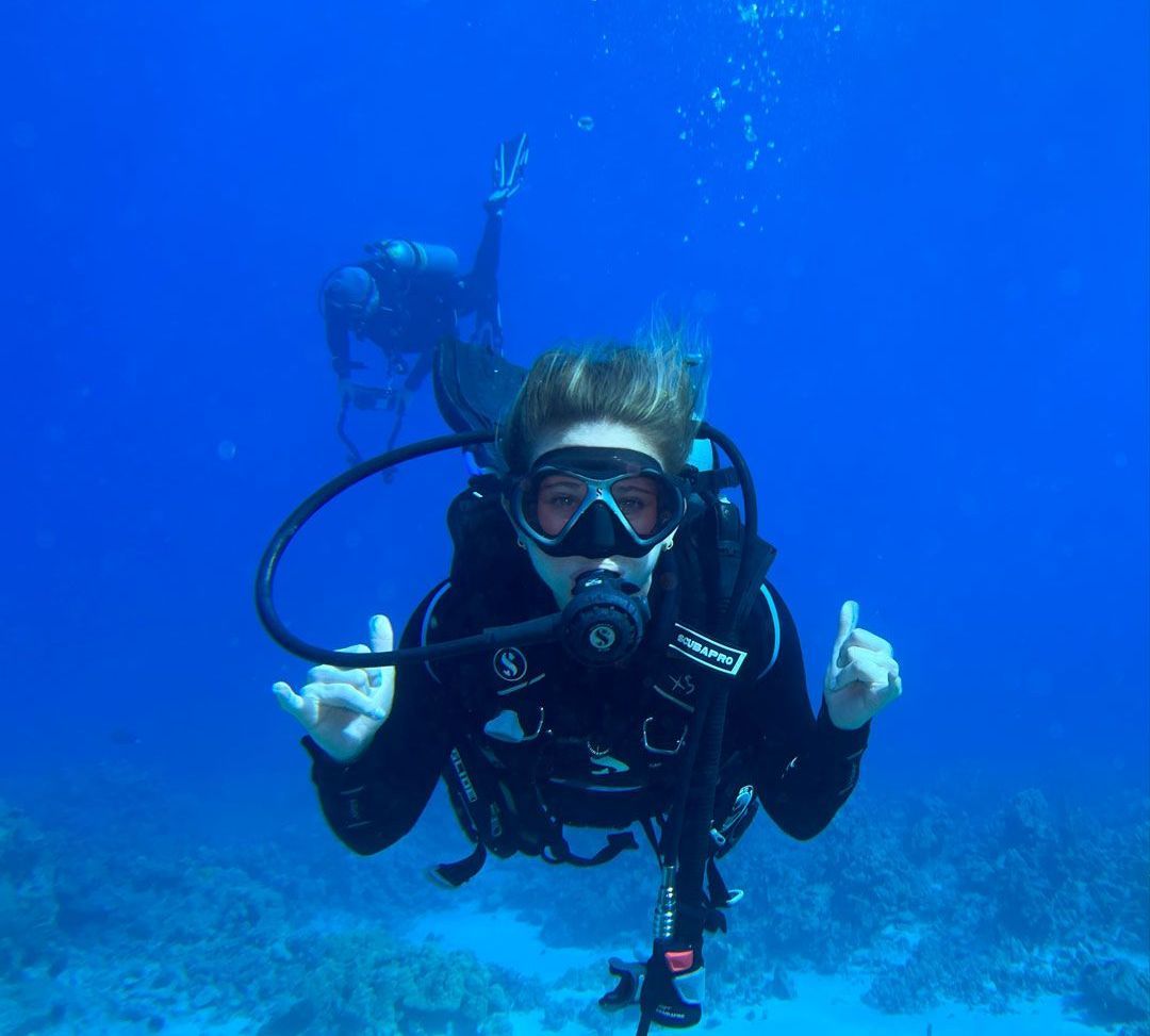 A person is swimming in the ocean with a scuba gear on.