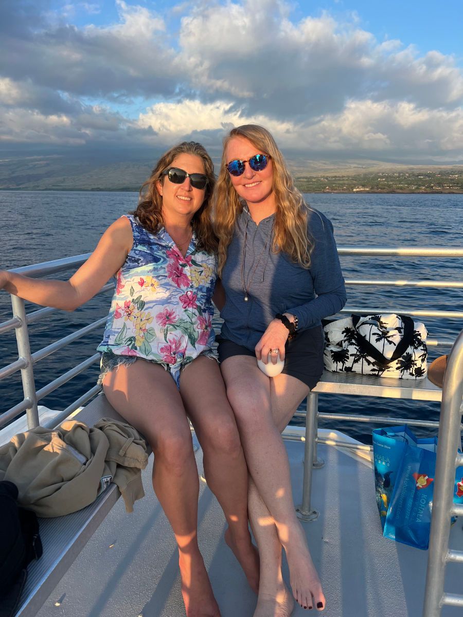 Two women are sitting on a boat in the water.