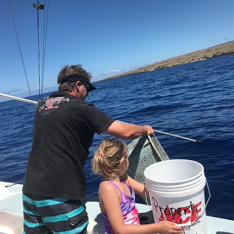 A man and a little girl are on a boat in the ocean.