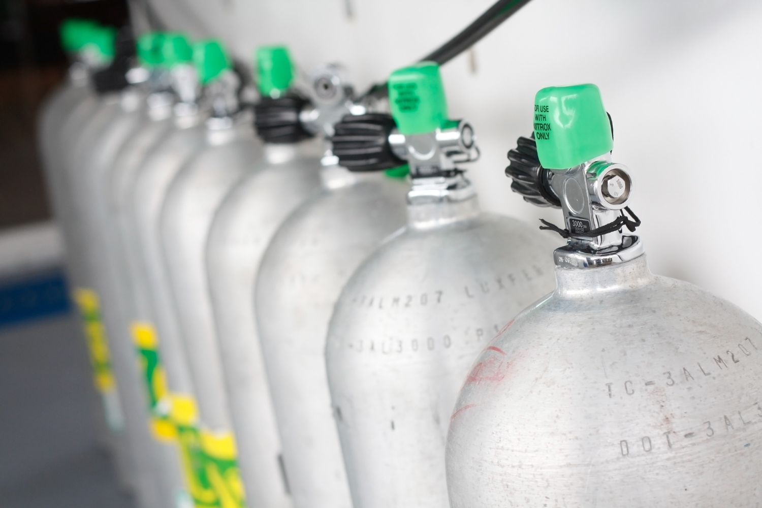 A row of scuba diving cylinders with green caps