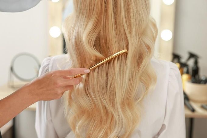 A Woman Is Getting Her Hair Done by A Hairdresser in A Salon — Main Hair Design in Armidale, NSW