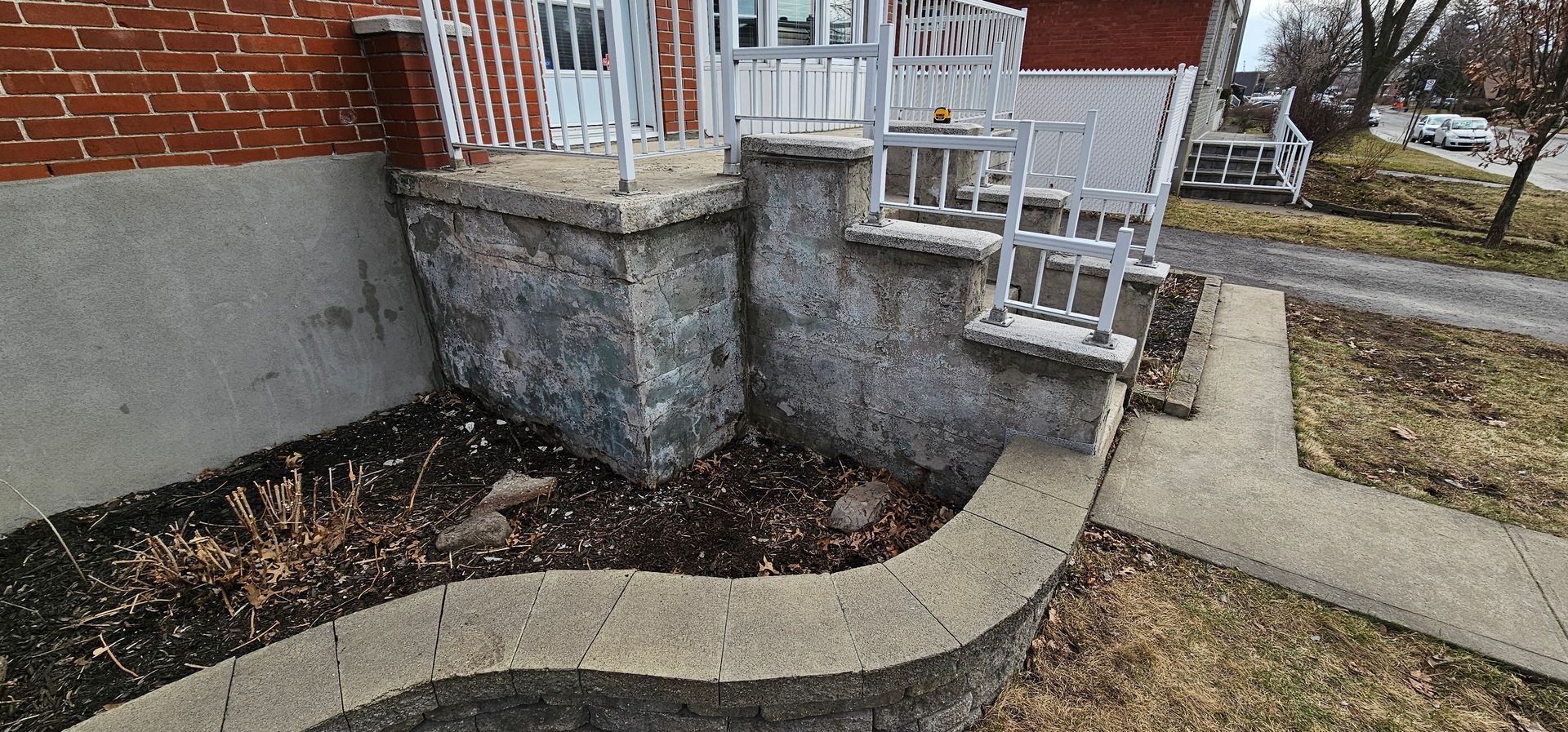 Un bâtiment en briques avec des escaliers qui y mènent et un trottoir devant.