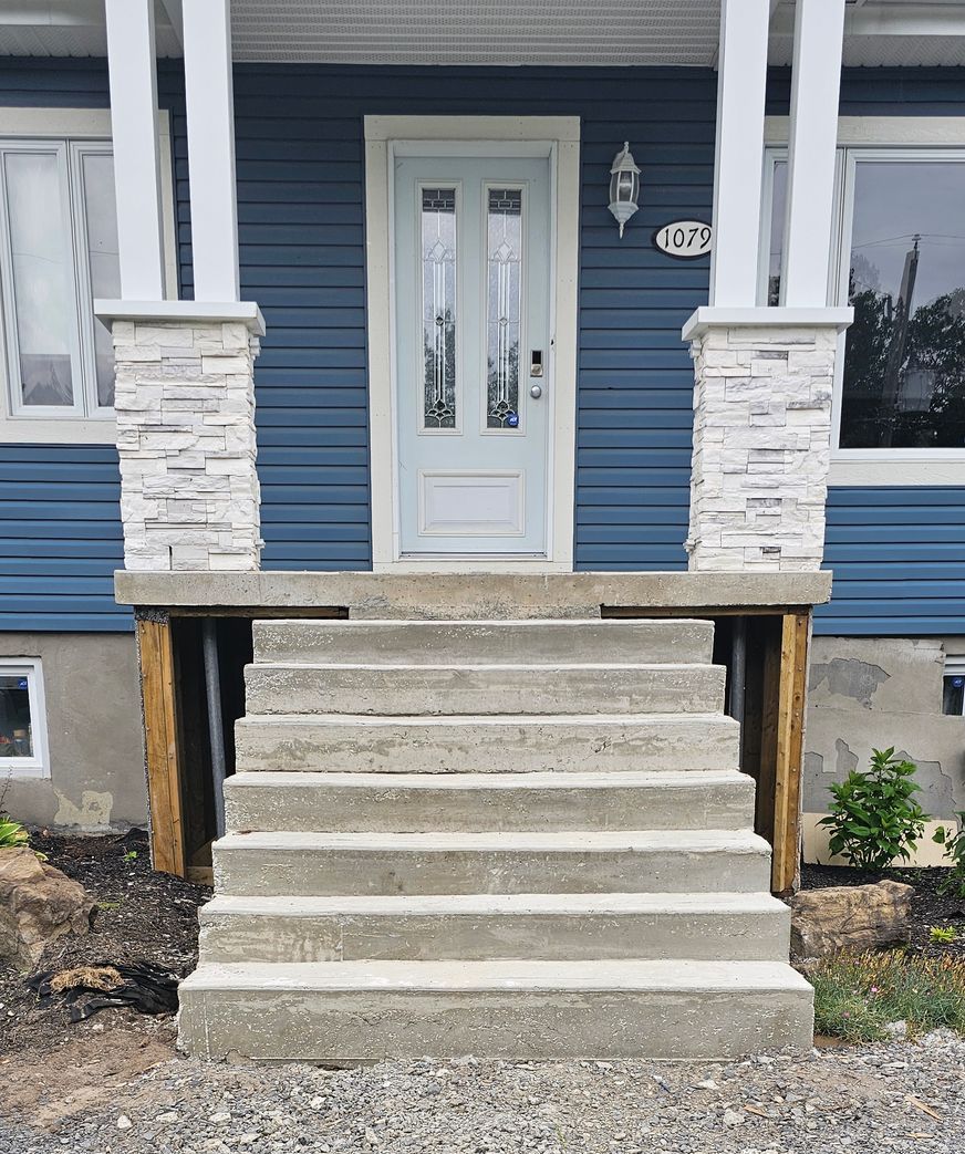 Une maison bleue avec des escaliers menant à la porte d'entrée