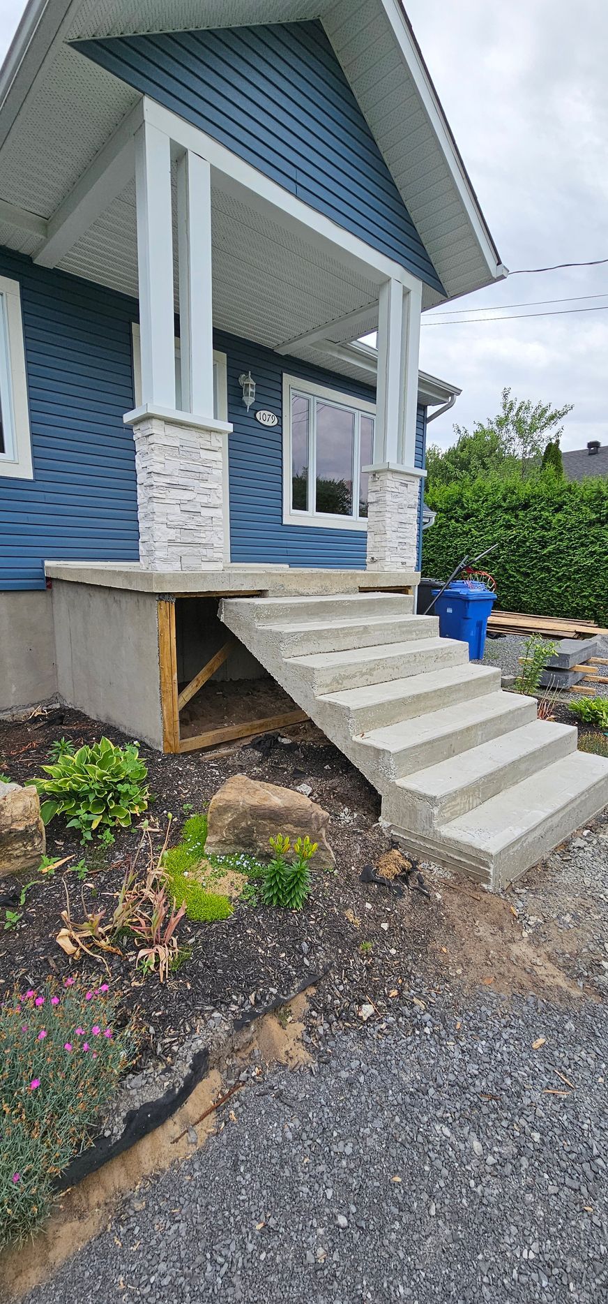 Une maison bleue avec des escaliers en béton menant au porche d'entrée.