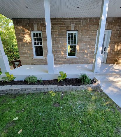 Une maison en brique avec un porche et une pelouse devant.