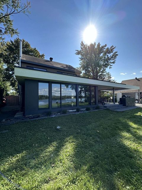 Une maison avec beaucoup de fenêtres et une grande pelouse devant elle