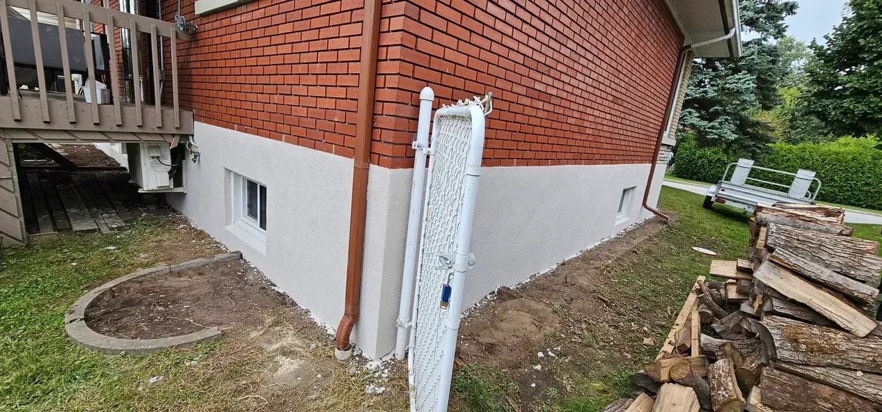 Une maison en briques avec une clôture blanche devant.