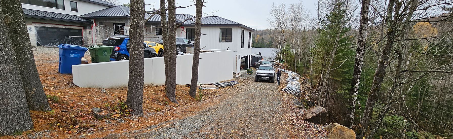 Une voiture est garée devant une maison dans les bois.