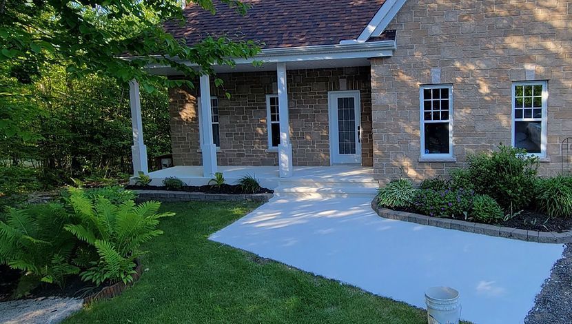 Une maison en brique avec un porche et une allée en béton qui y mène.