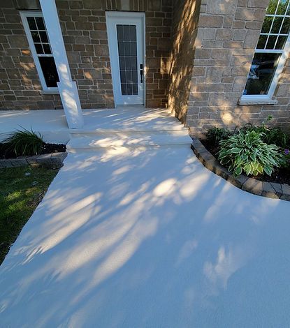 Une allée en béton menant à la porte d'entrée d'une maison en briques.