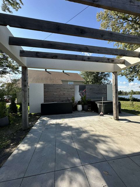 Un patio avec une pergola au-dessus et une maison en arrière-plan