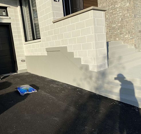 Un bâtiment en briques blanches avec des escaliers et un sac de sable sur le sol.
