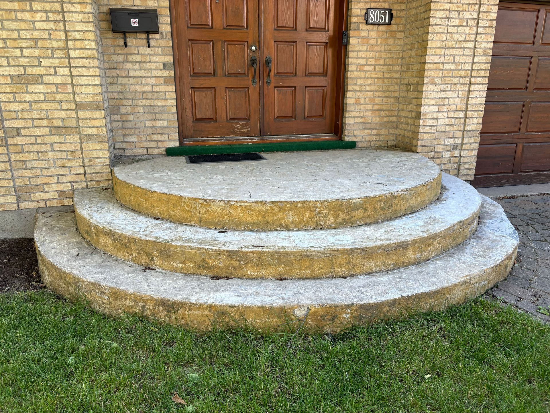 Un ensemble de marches en béton menant à la porte d'entrée d'une maison en briques.