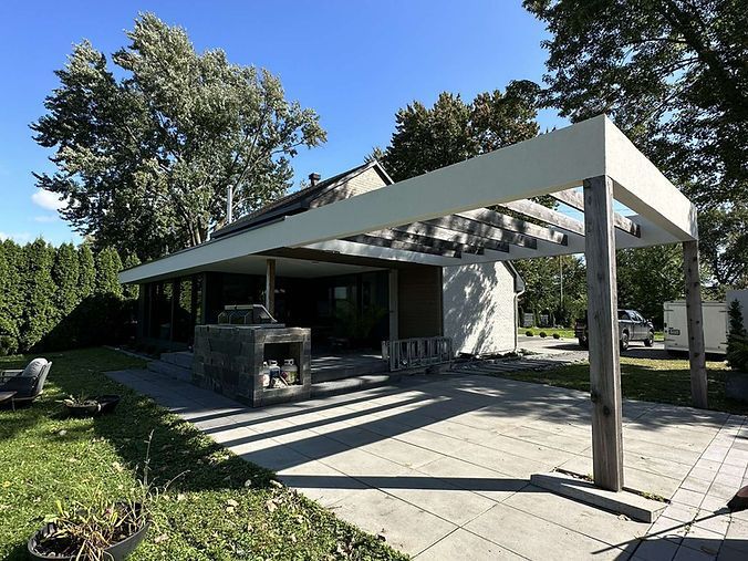 Une maison avec une pergola et un patio devant.