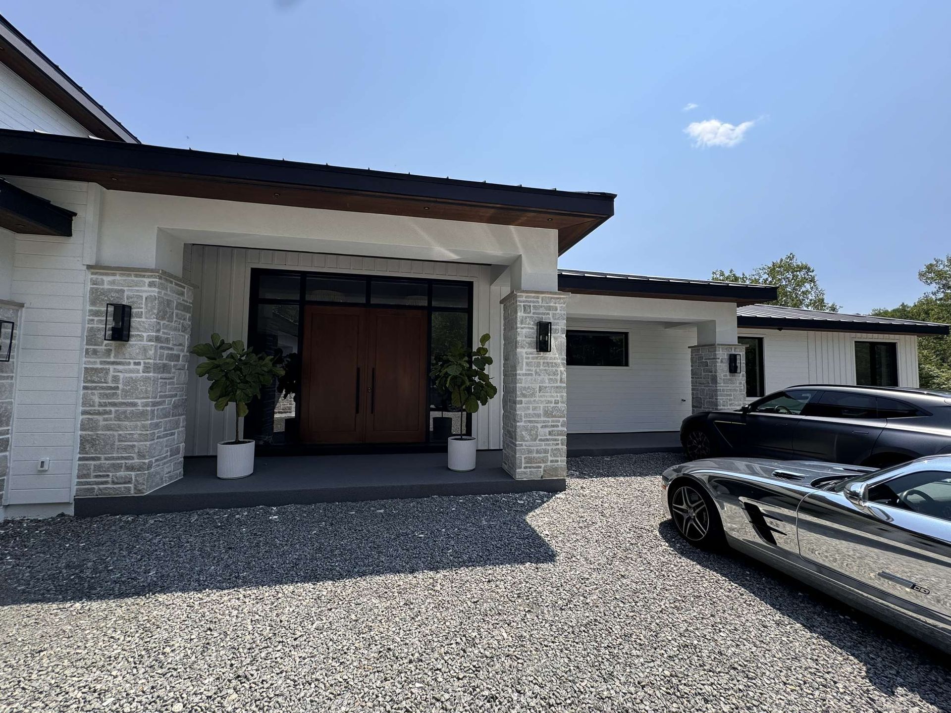 Une voiture argentée est garée devant une maison blanche.