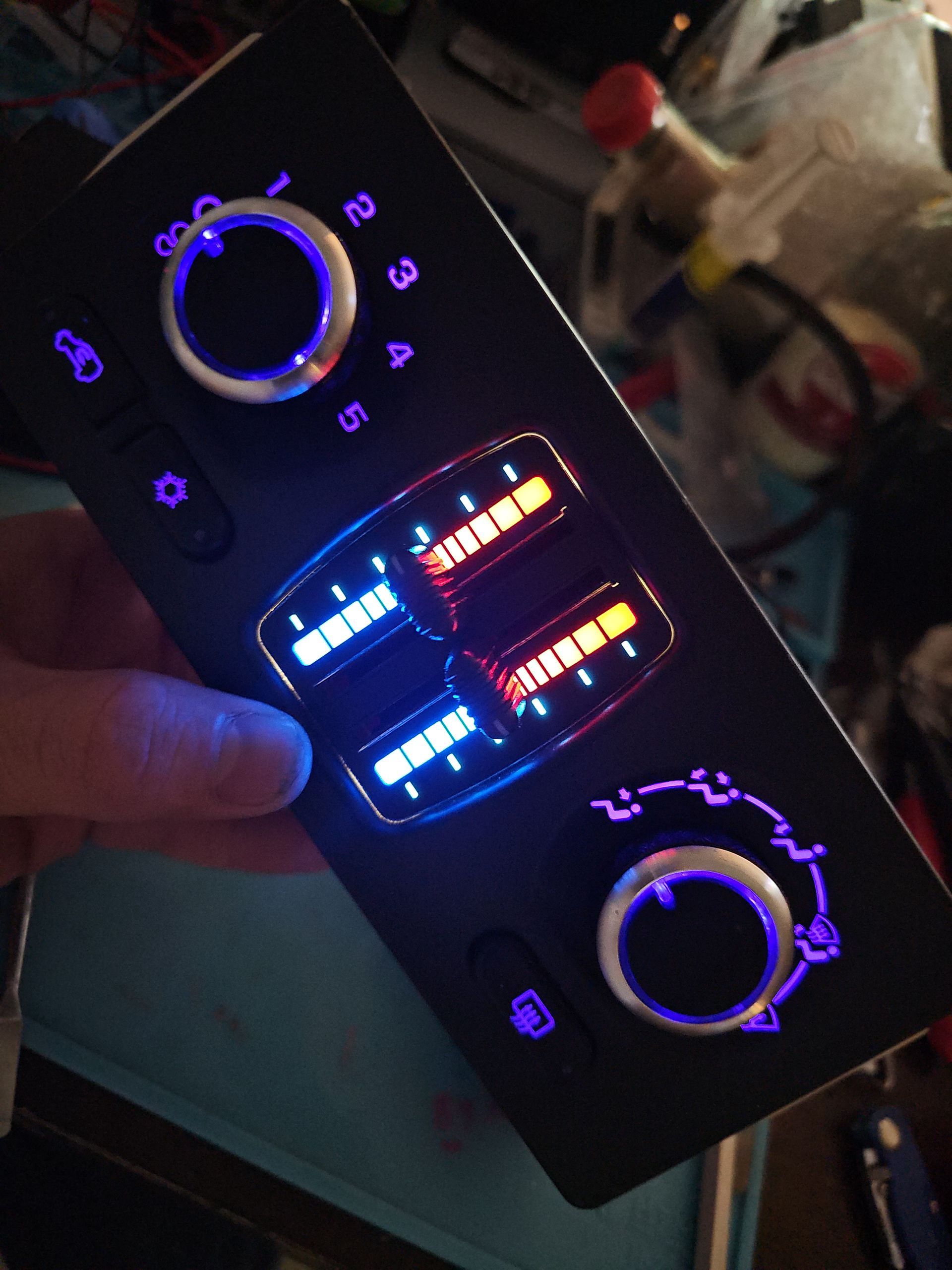 A person is holding a remote control with purple lights on it.