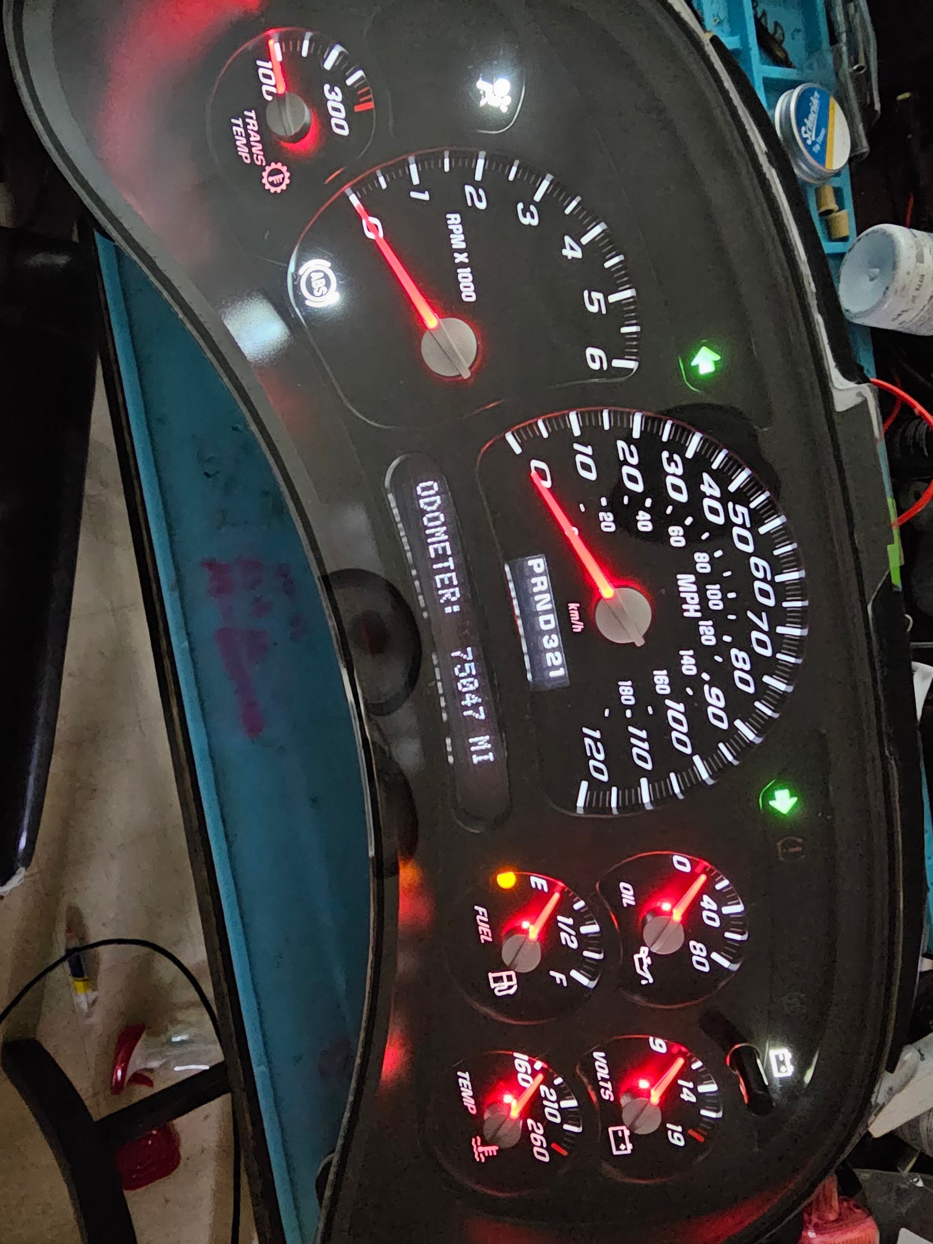 A close up of a car dashboard with a red speedometer