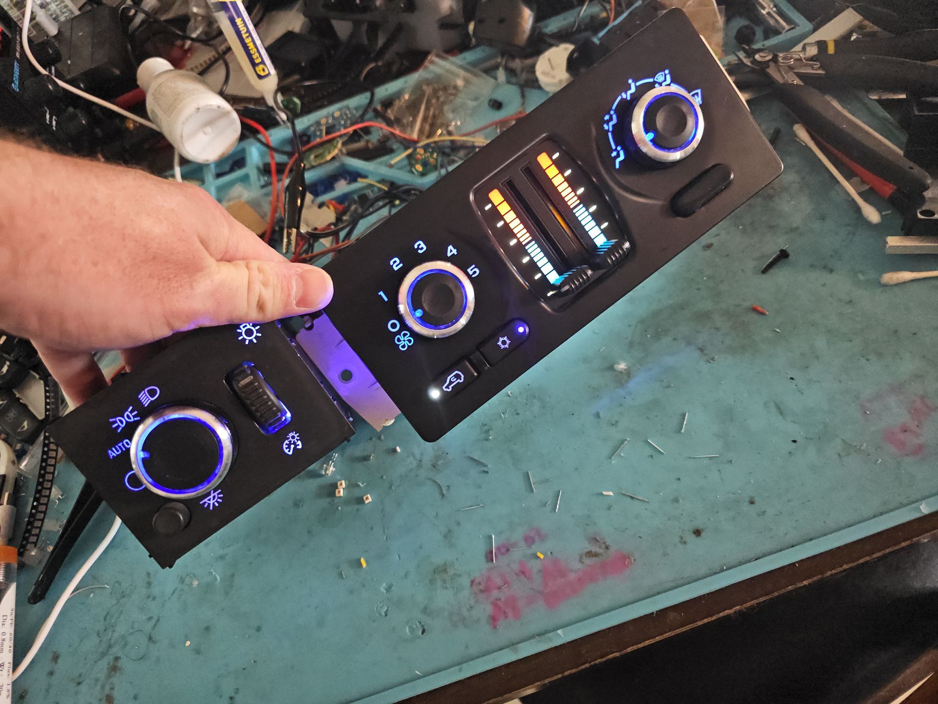 A person is holding a piece of electronic equipment on a table.