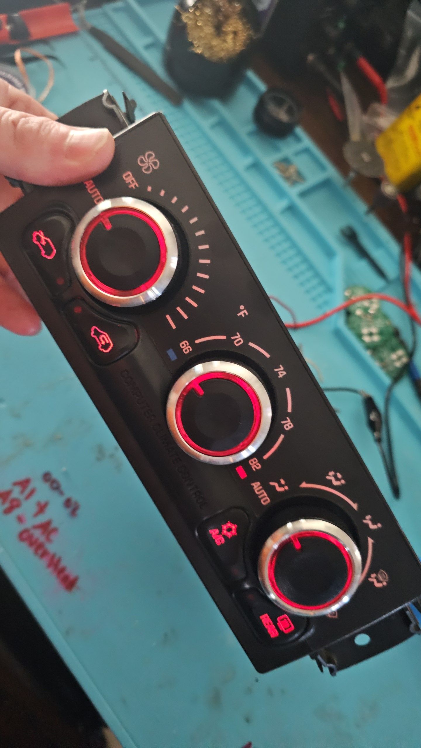 A person is holding a black control panel with red knobs