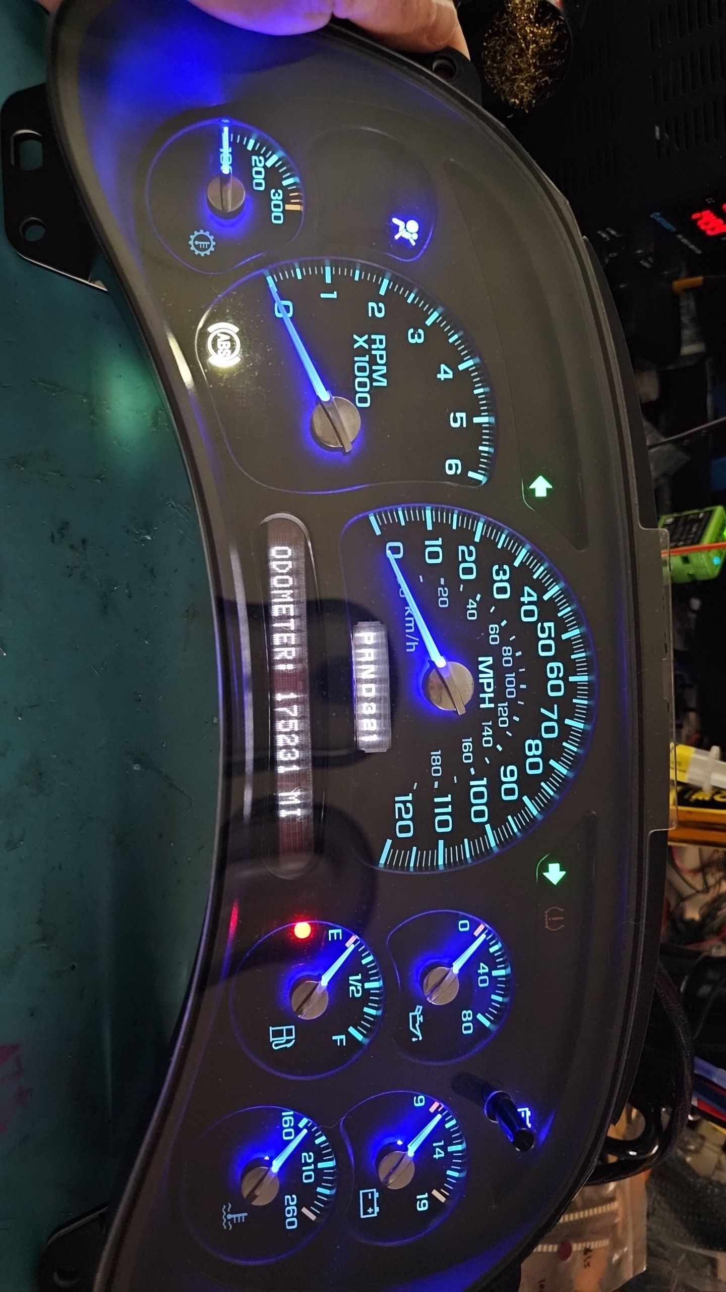 A person is holding a black dashboard with blue lights on it.