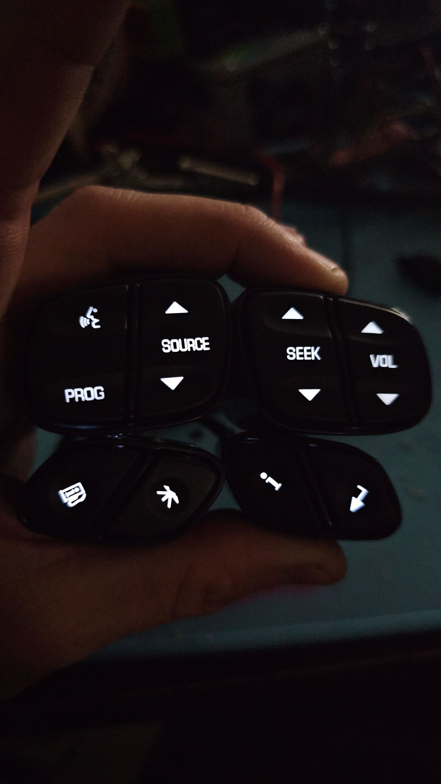 A person is holding a remote control with buttons that say source seek and volume
