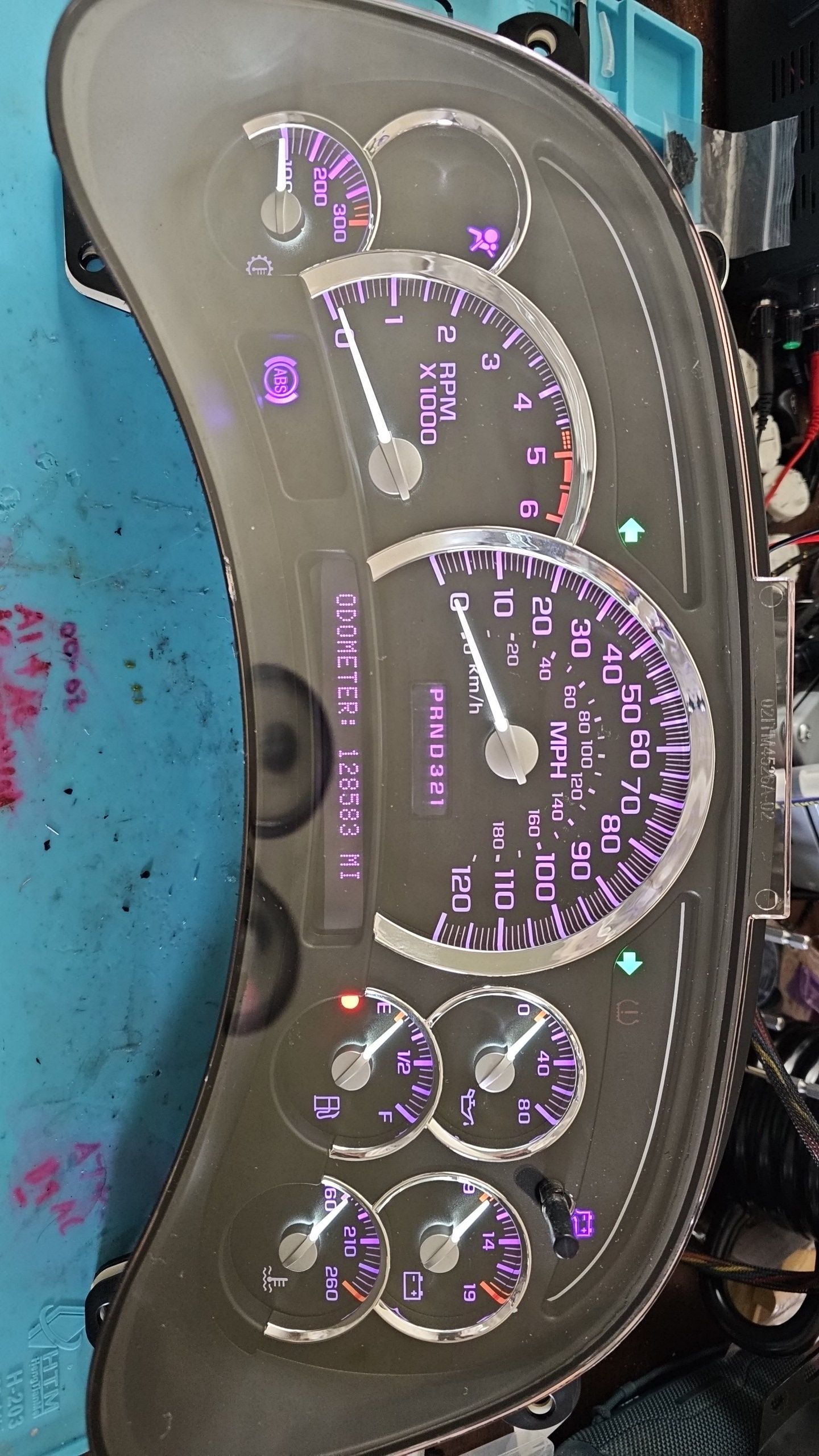 A close up of a car dashboard with purple gauges
