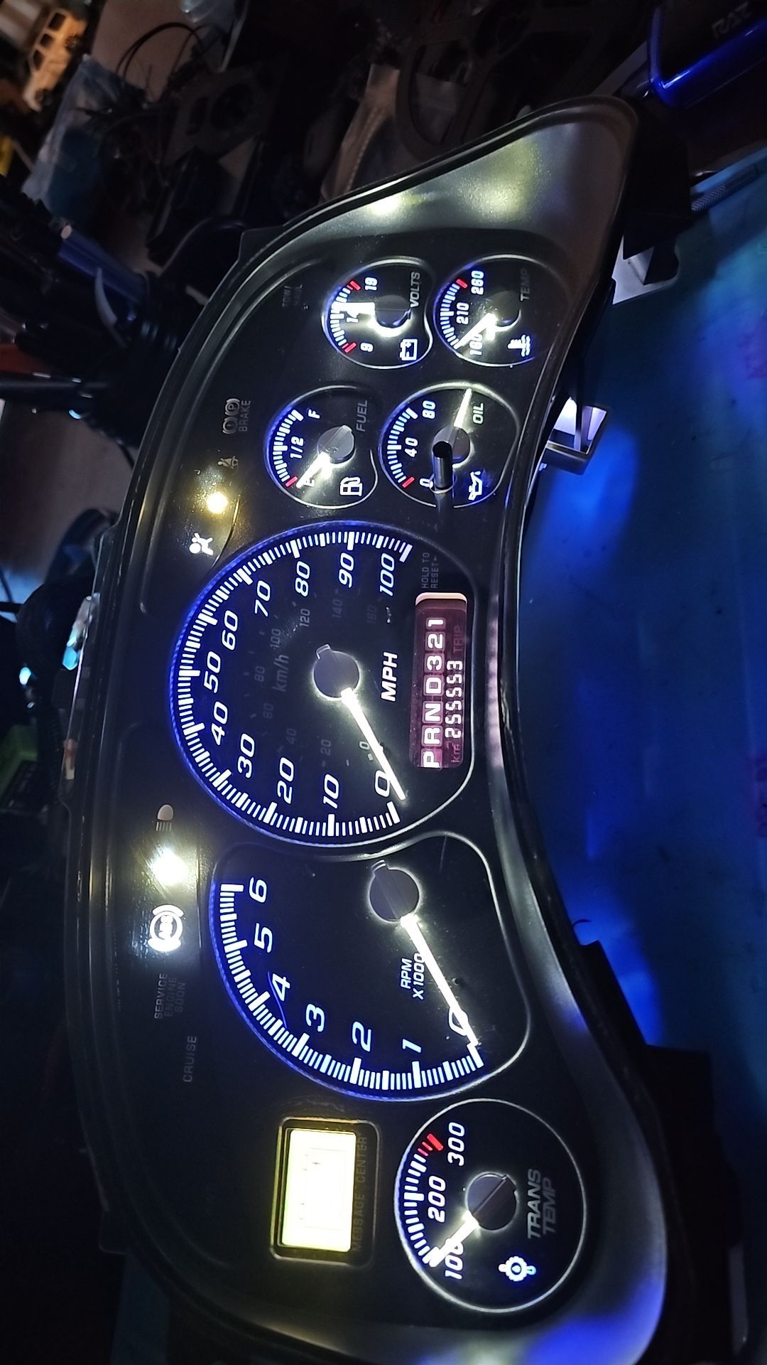 A close up of a car dashboard with blue lights on it.
