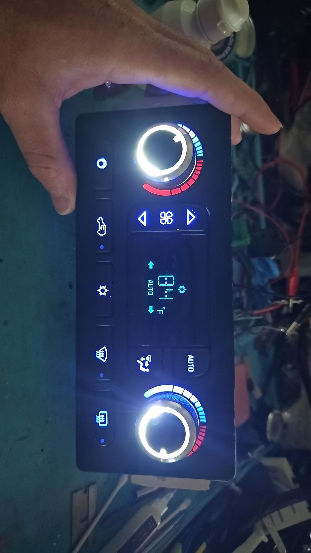 A person is holding a car a/c control panel in their hand.