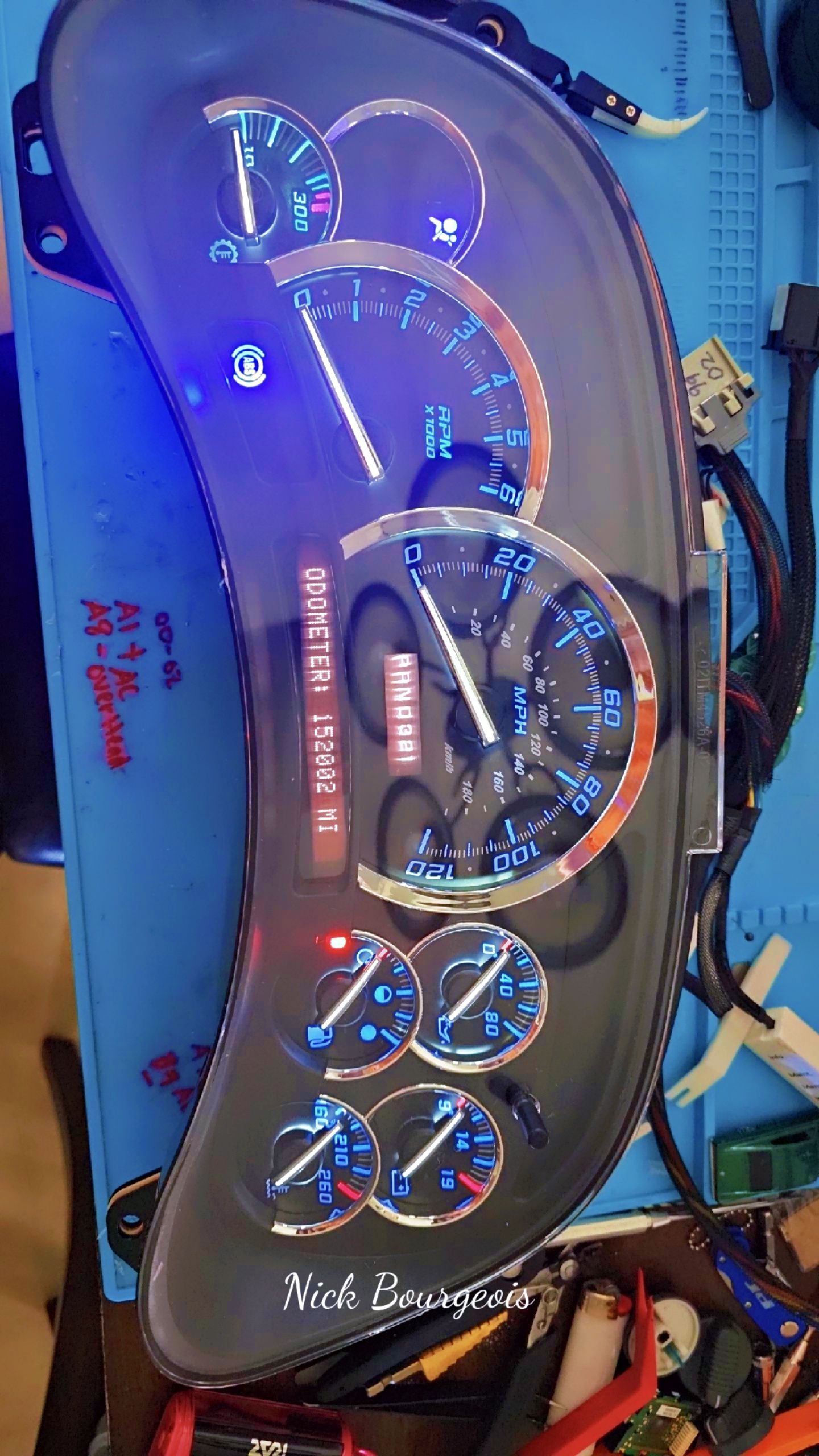 A speedometer is sitting on a table with a blue light on it.