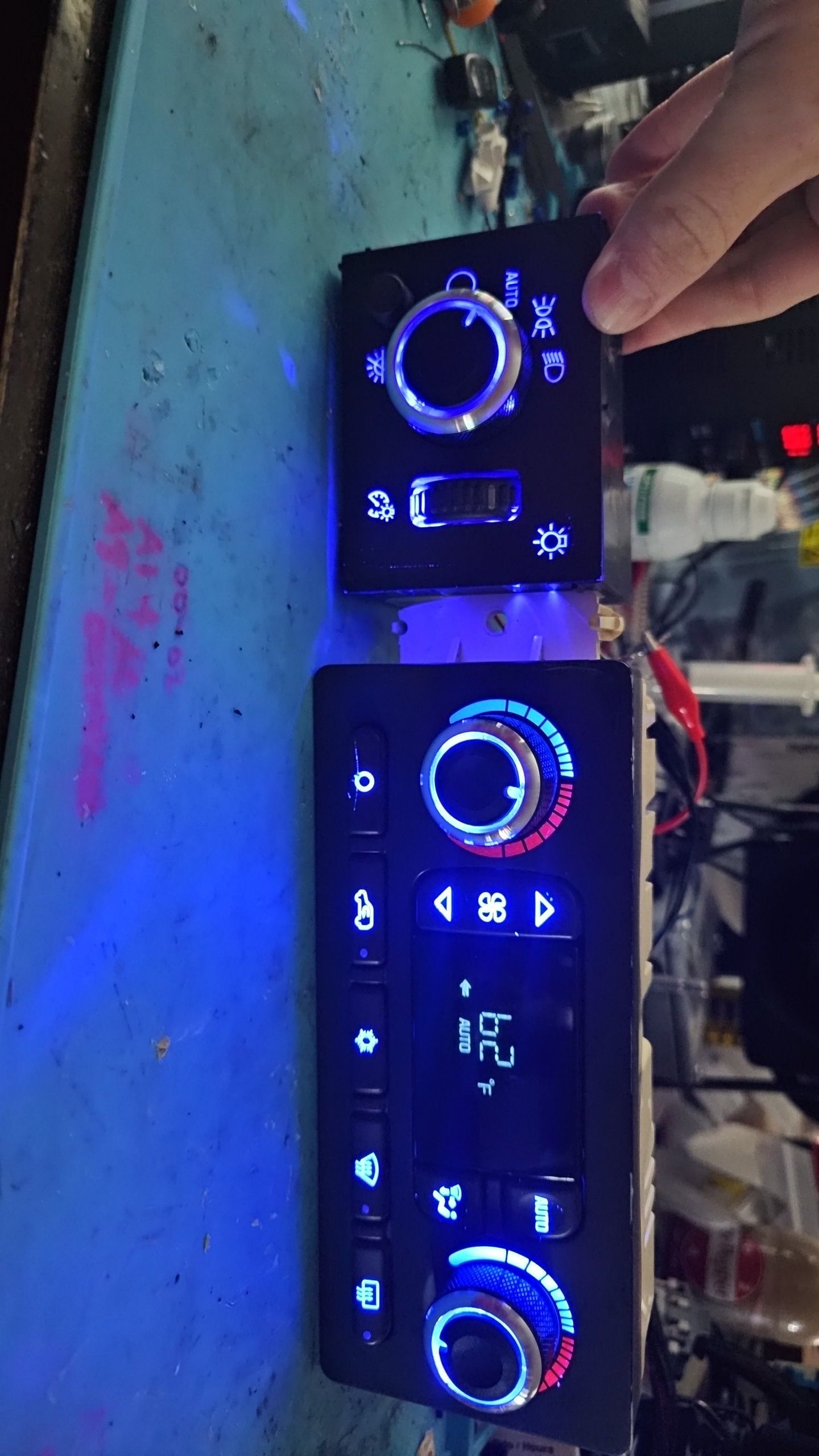 A person is adjusting a car a/c control panel on a table.