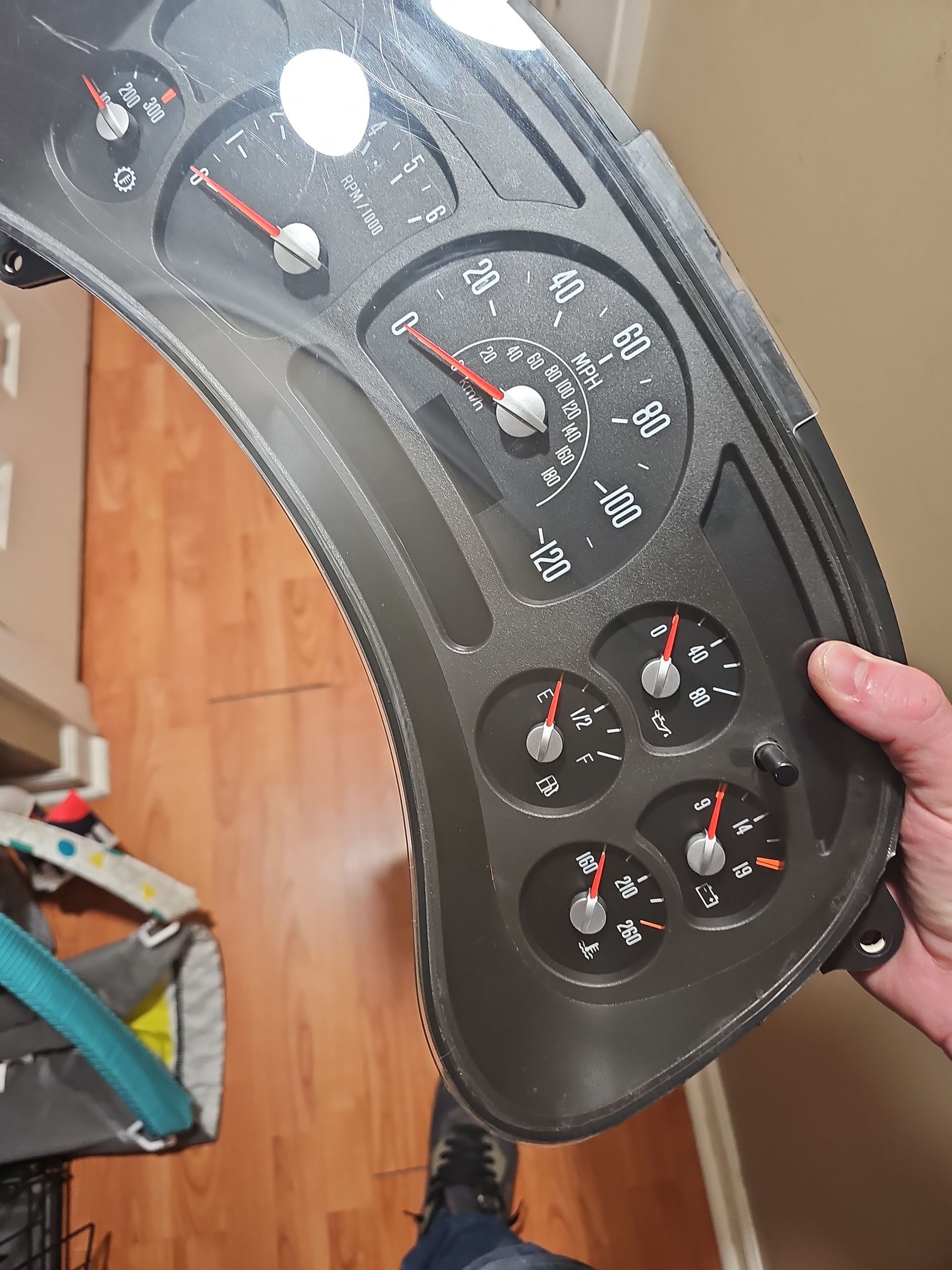 A person is holding a black dashboard with red numbers