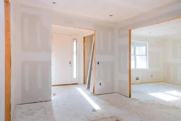 An empty room in a house under construction with drywall on the walls.