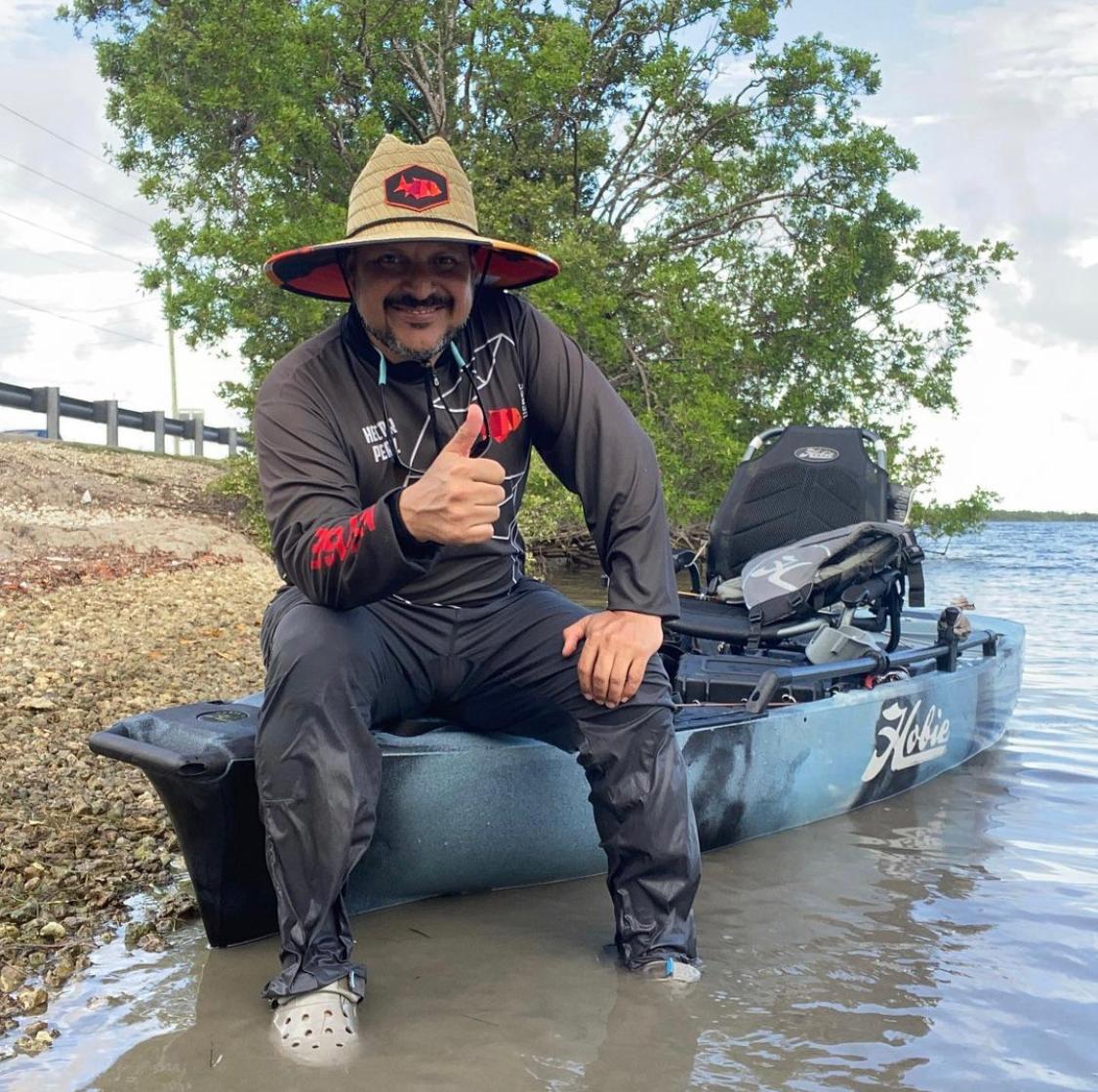 Un hombre está sentado en un kayak en el agua levantando el pulgar.