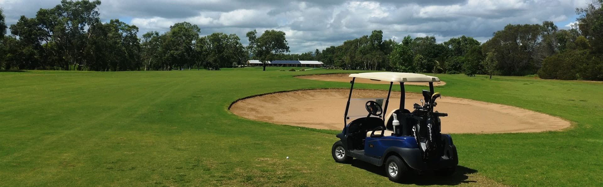 A Golf Cart Is Parked In The Grass On A Golf Course — Rowes Bay Golf Club In Rowes Bay, QLD