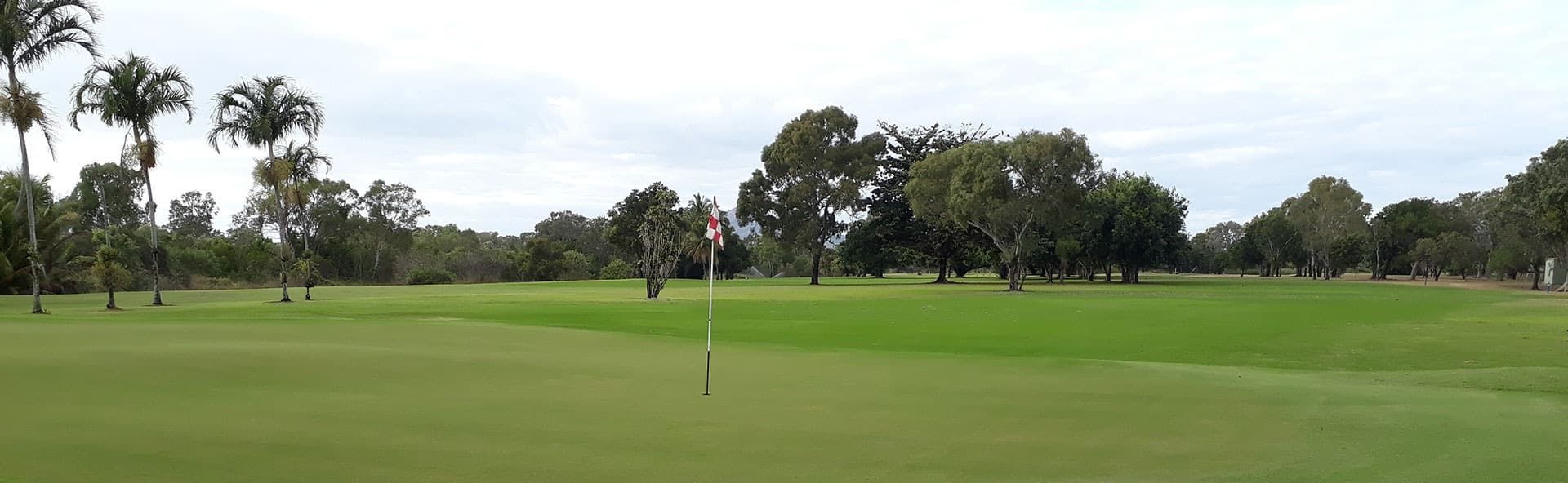 A Golf Course With Trees In The Background And A Flag On The Green — Rowes Bay Golf Club In Rowes Bay, QLD