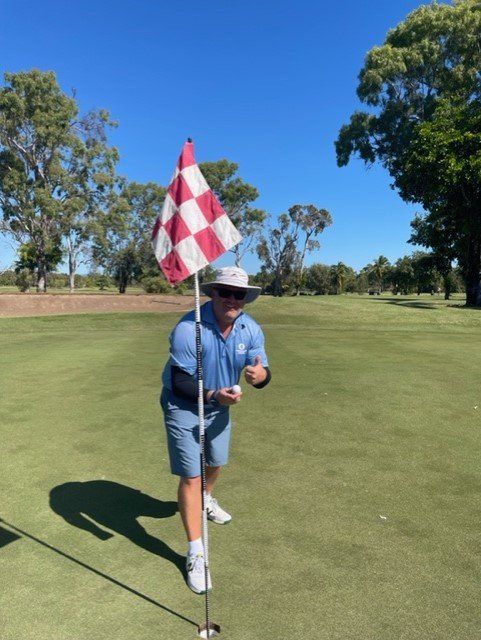 A Man Standing Next To A Flag On A Golf Course — Rowes Bay Golf Club In Rowes Bay, QLD
