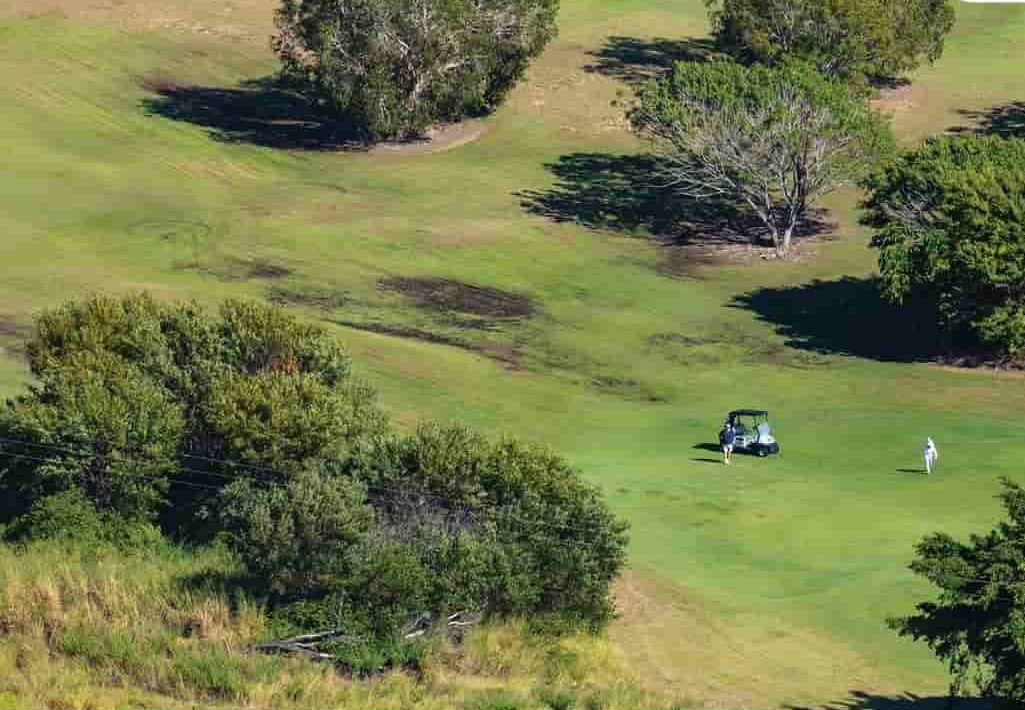 A Golf Cart Is Parked On The Green Of A Golf Course Surrounded By Trees — Rowes Bay Golf Club In Rowes Bay, QLD