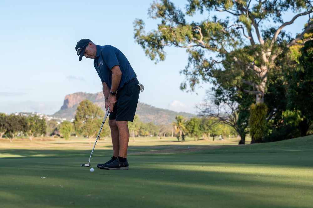 A man is putting a golf ball on a golf course— Rowes Bay Golf Club In Rowes Bay, QLD