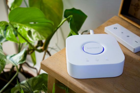 A white device is sitting on a wooden table next to a plant.