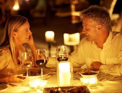A man and a woman are sitting at a table with wine glasses and candles.