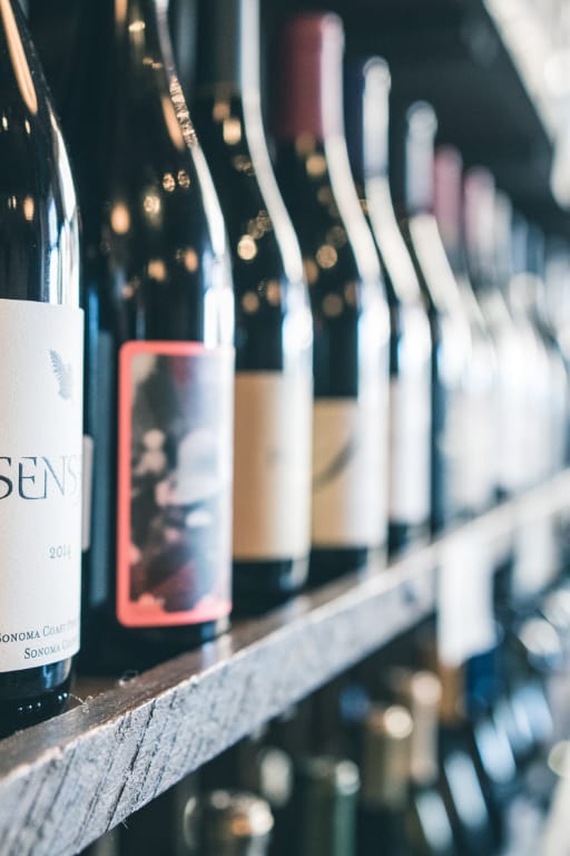 Several bottles of wine are lined up on a shelf including a bottle of sen