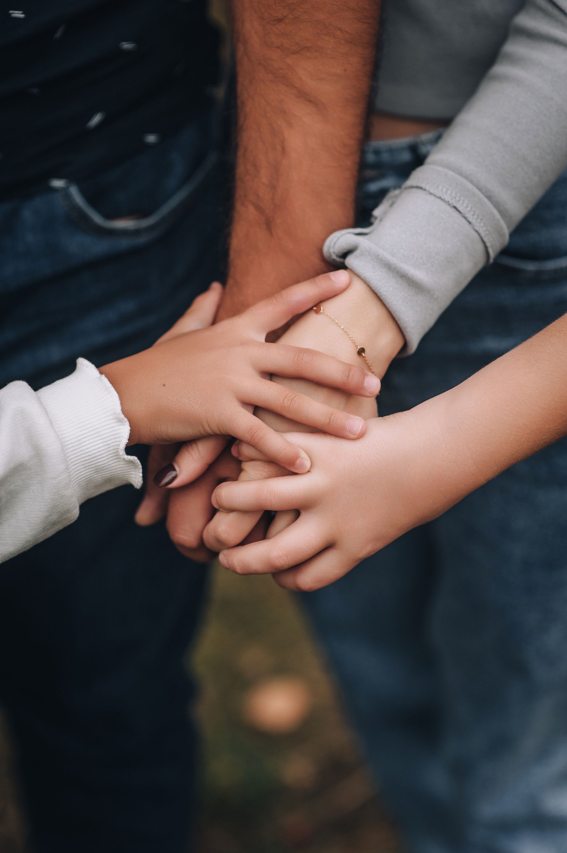 Three sets of hands are stacked together on top of one another, signaling unity and connection. Three sets of hands are stacked together on top of one another, signaling unity and connection.