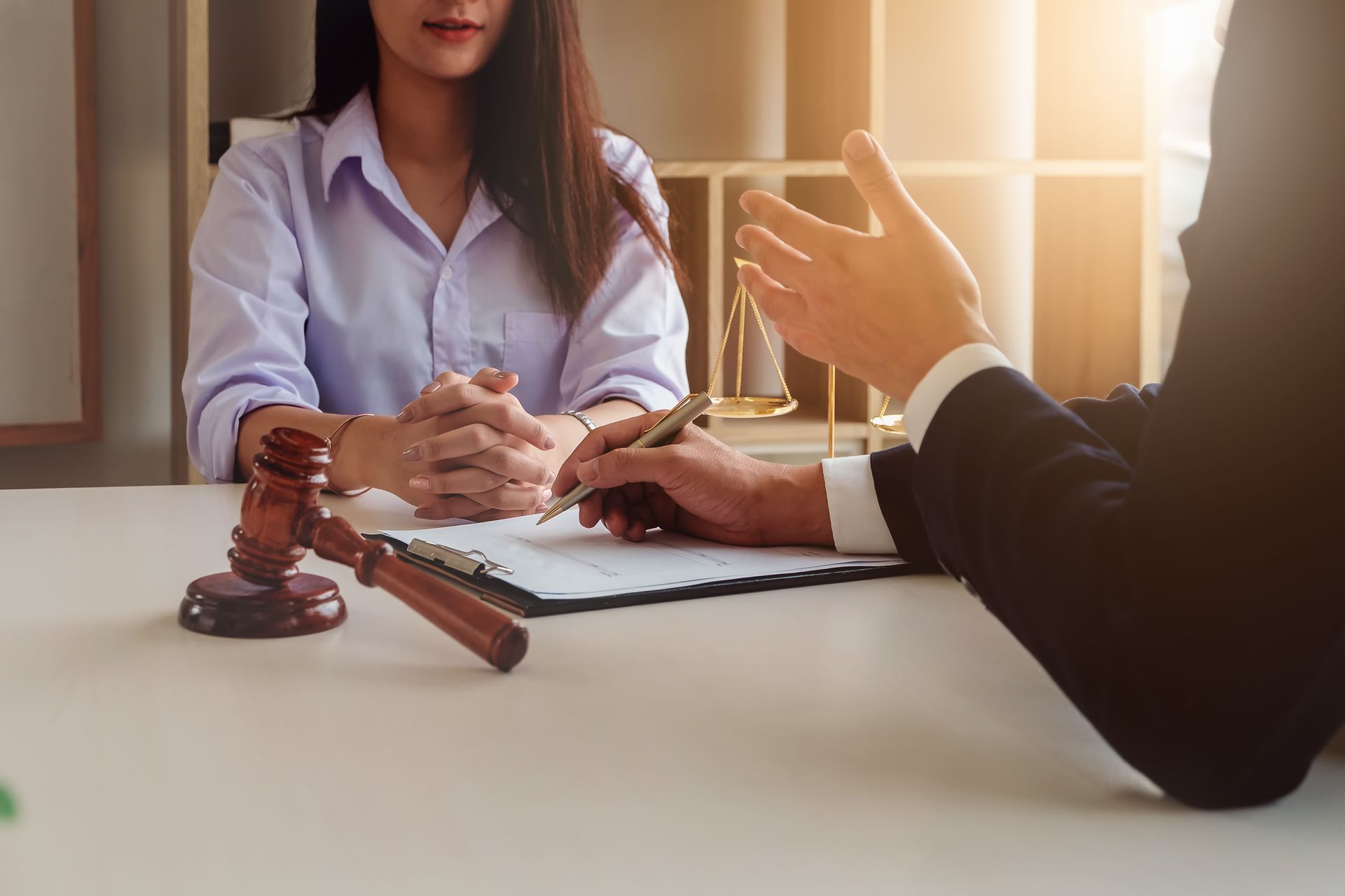 A lawyer consults with a client in an office, with a wooden gavel resting on the table near legal documents.