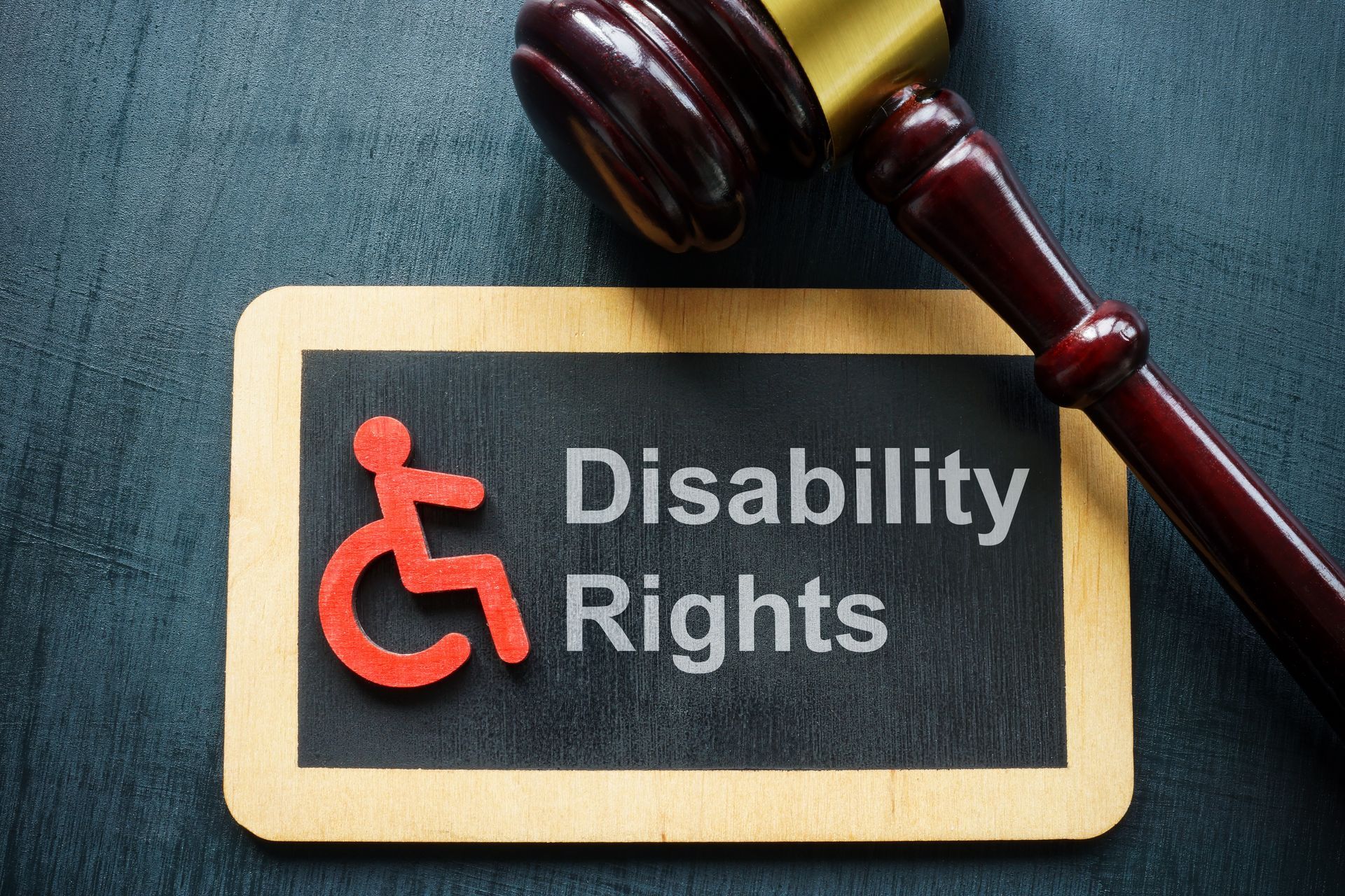 A gavel rests beside a sign displaying a disability symbol and the words “Disability Rights.” A gavel rests beside a sign displaying a disability symbol and the words “Disability Rights.”