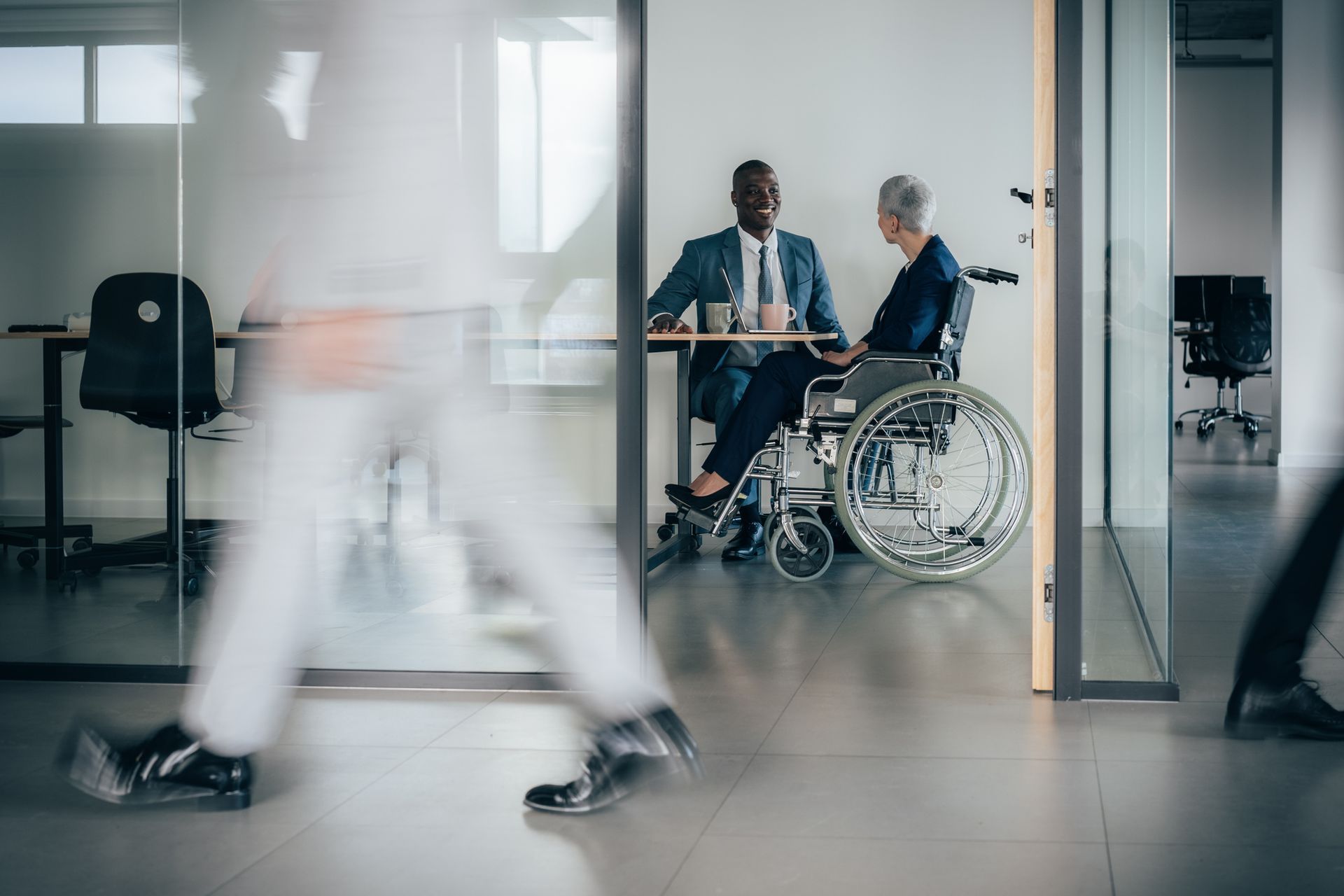 A disability law attorney meets a client in a wheelchair at a modern office. A disability law attorney meets a client in a wheelchair at a modern office.