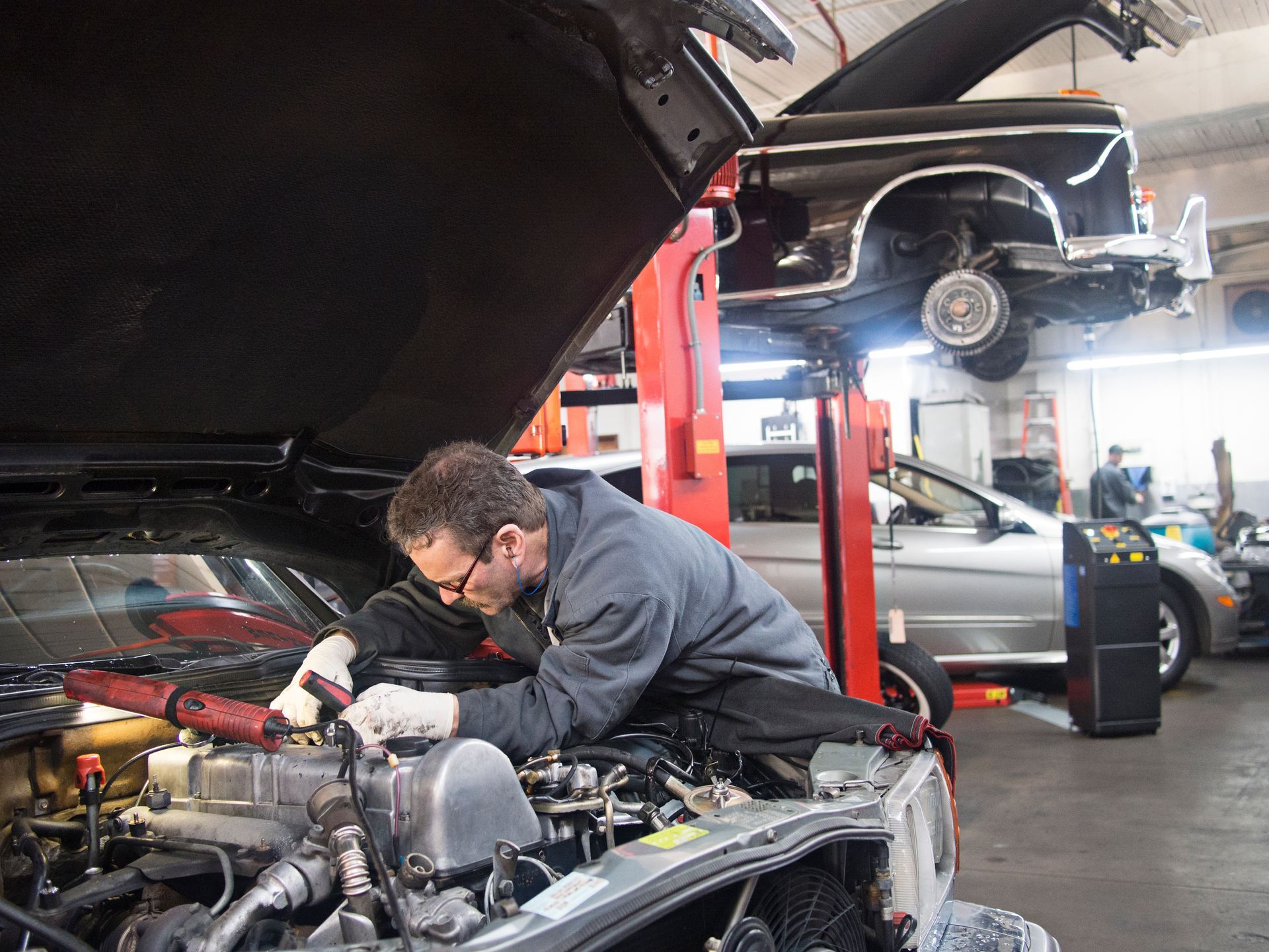 A man is working on the engine of a car in a garage.